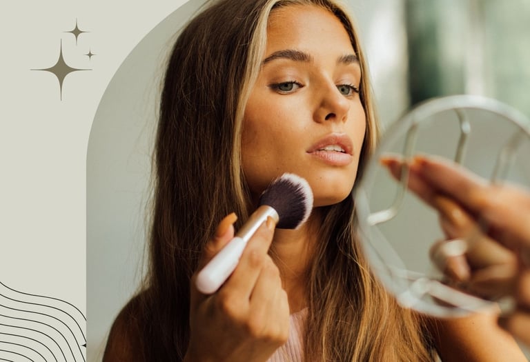 A woman applying makeup with a fluffy brush while looking into a handheld mirror for a beauty routine.