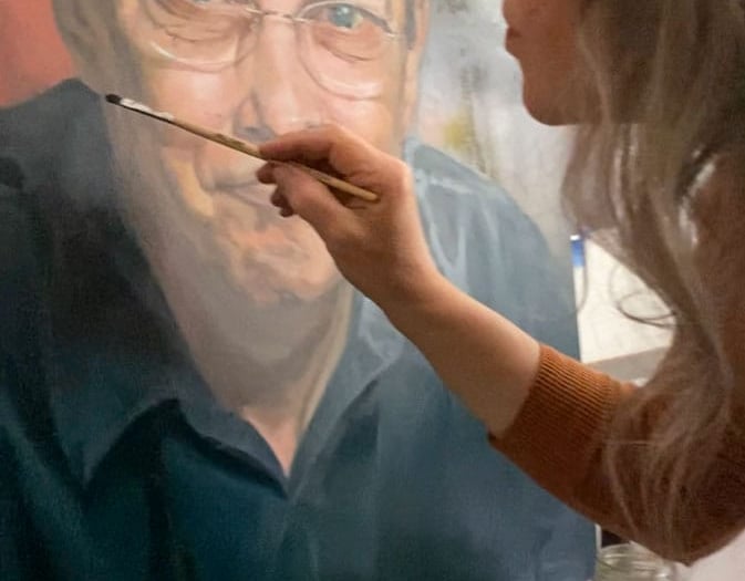 Close up on Stefanie painting on a large oil portrait.