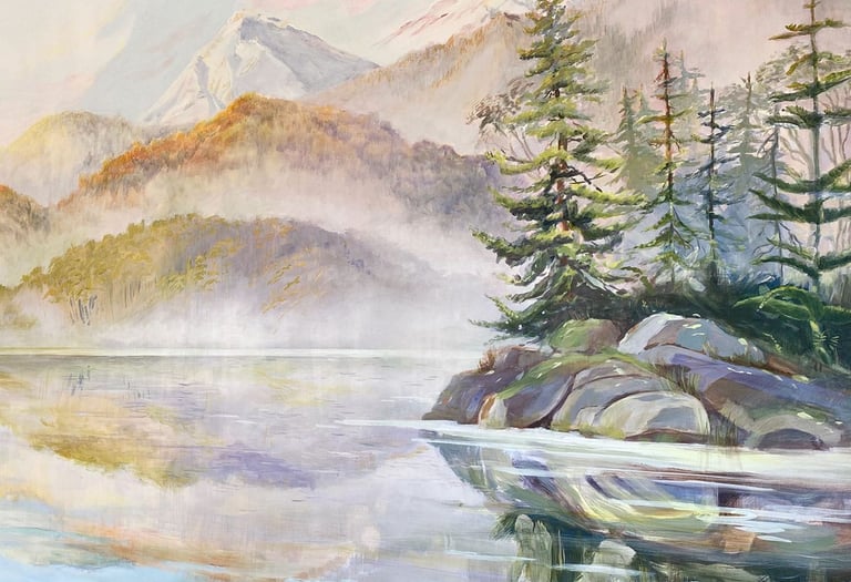 A forested island in front of foggy mountains reaching down to the shore.