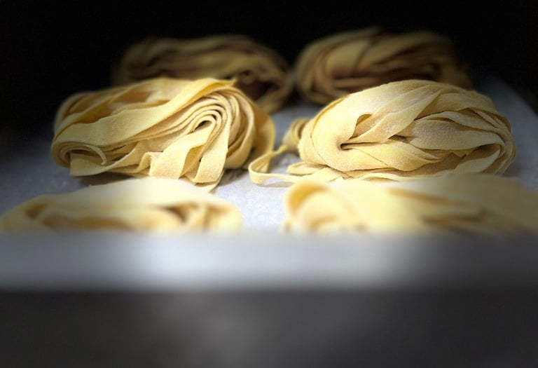 Frisch zubereitete hausgemachte Tagliatelle auf einem traditionellen Holzbrett.