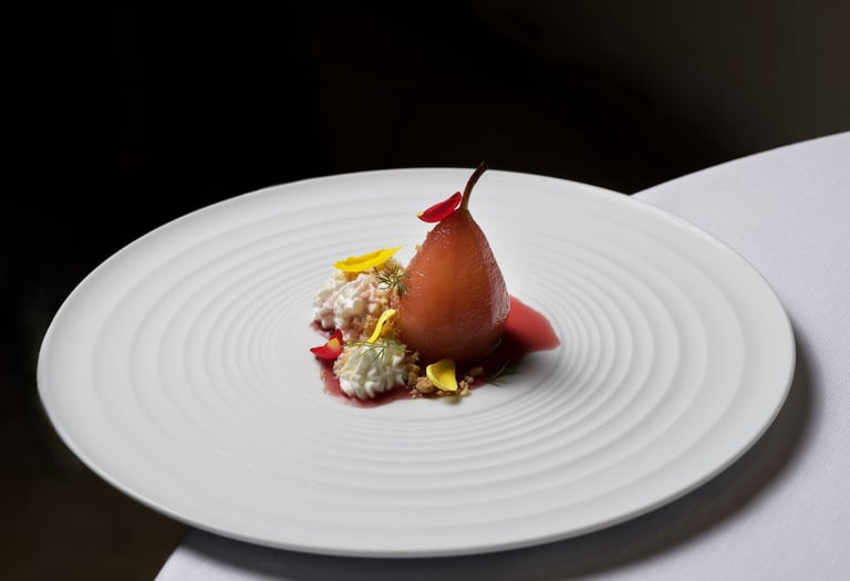 Pera cotta nel vino rosso servita su piatto bianco minimalista - Gourmet poached pear in red wine, e