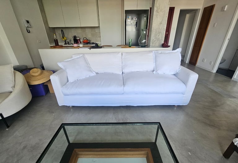 Sala de estar moderna com um sofá de tecido branco e uma mesa de centro de vidro em um apartamento 
