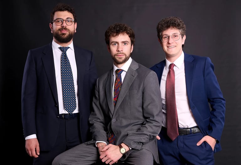 Three lawyers wearing formal suits and ties posing for a corporate group portrait.