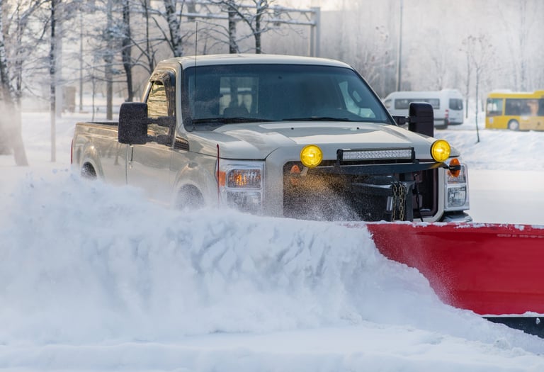 Snowplow truck clearing snow from parking lot after snow storm