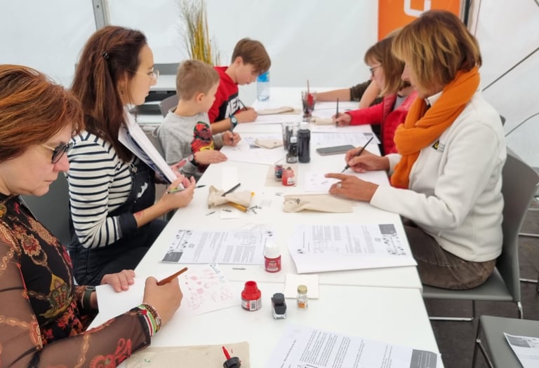 Photographie de Camille Poli encadrant un atelier pédagogique pour enfants et adultes