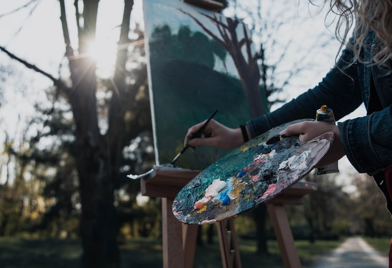 A woman artist, painting with a palette outside.