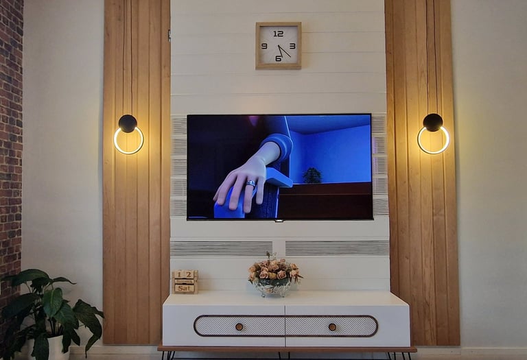 Modern living room TV wall unit with wood panels, circular LED lights, and white TV stand.