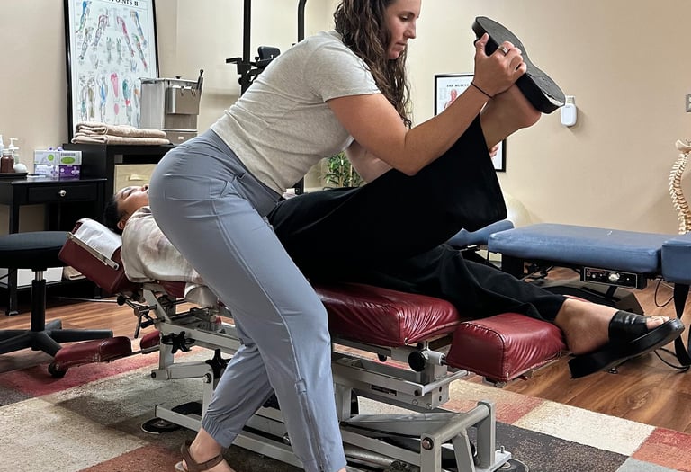 Chiropractor performing nerve tension test on patient laying face up on chiro table. 