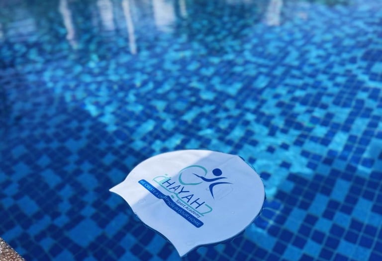 White Hayah7 Sport Academy swimming cap floating in a blue tiled outdoor pool.