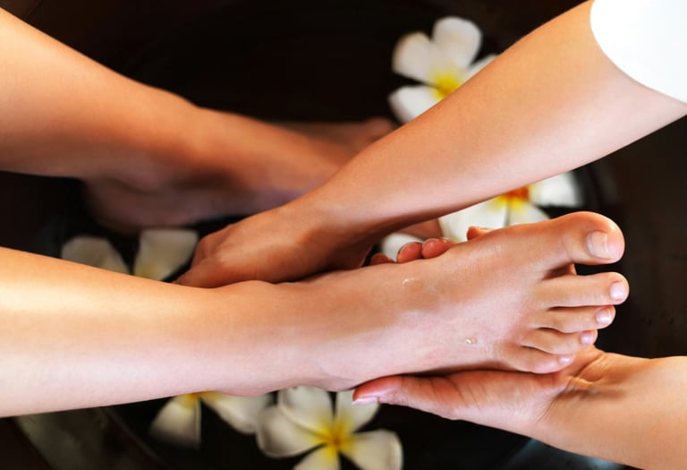 Relaxing foot massage and spa treatment in a bowl of water with frangipani flowers.