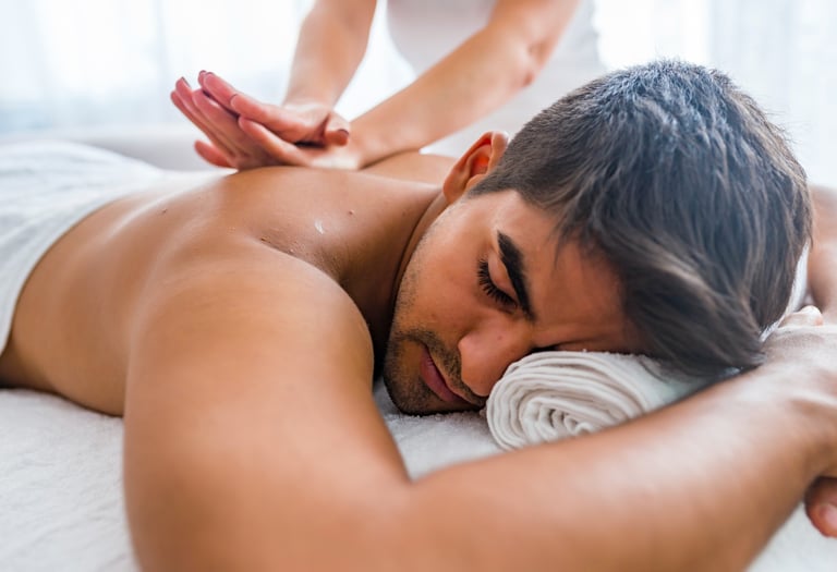 A man receives a relaxing deep tissue back massage from a therapist at a luxury wellness spa.