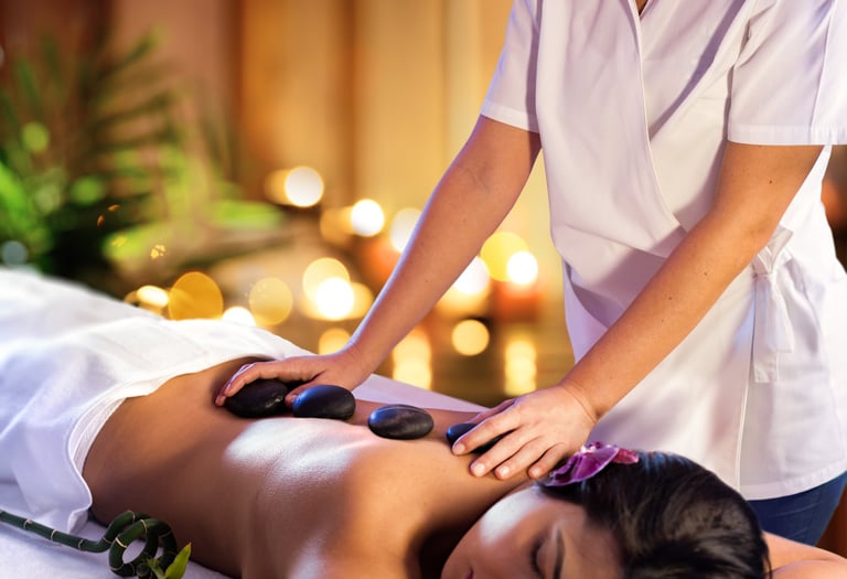 Professional massage therapist performing a hot stone massage treatment for a woman at a luxury spa.