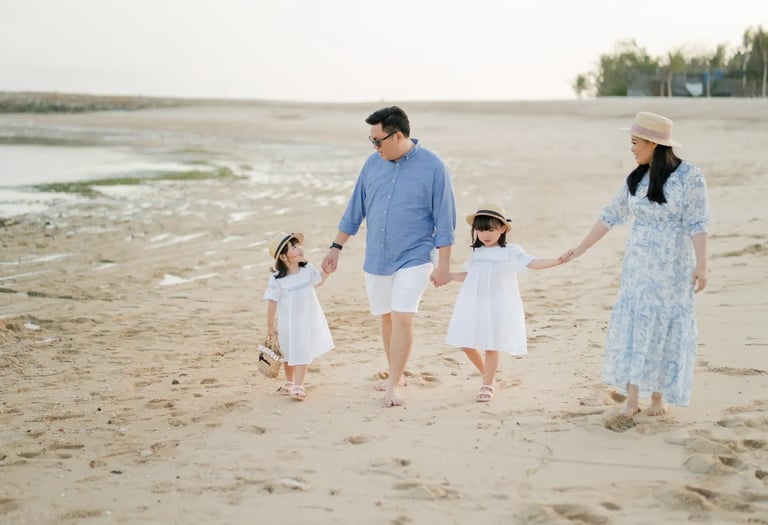 Parents walking with their daughters on the beach at The Apurva Kempinski Bali.