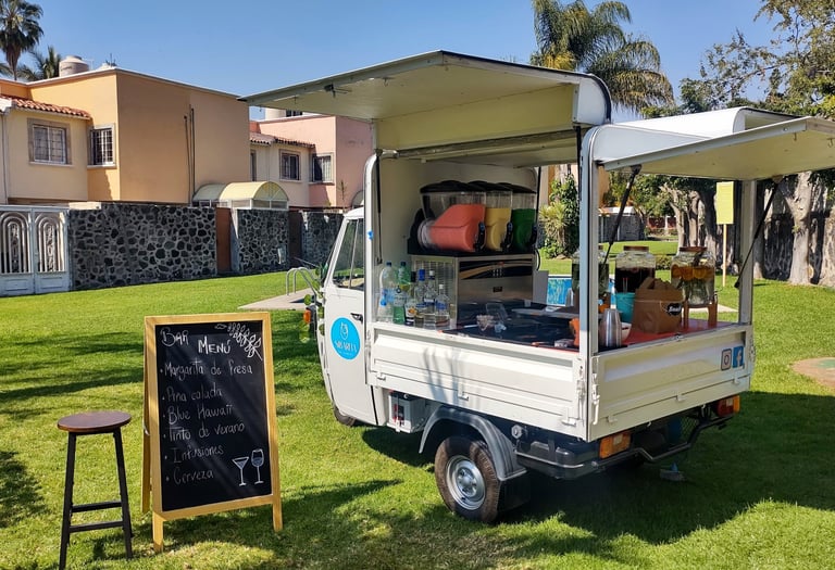 Piaggio italiano convertido en food truck con servicio de barra móvil de bebidas, en evento de día