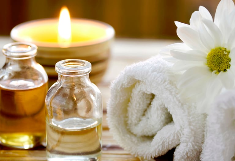 oleos para massagem, vela, toalha e uma flor