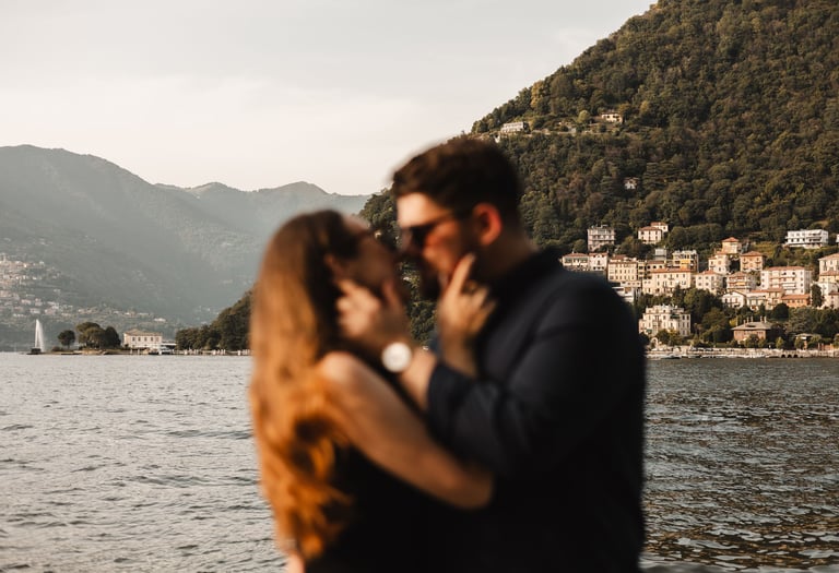 a man and woman kissing in front of a mountain