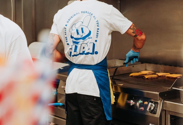 Cuiner de Flipa Burger preparant hamburgueses a la planxa amb l’uniforme de la marca