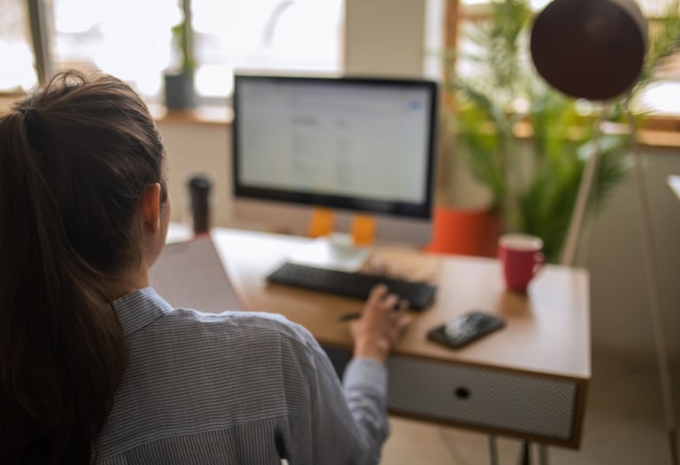a woman sitting at a desk with a computer and a ball