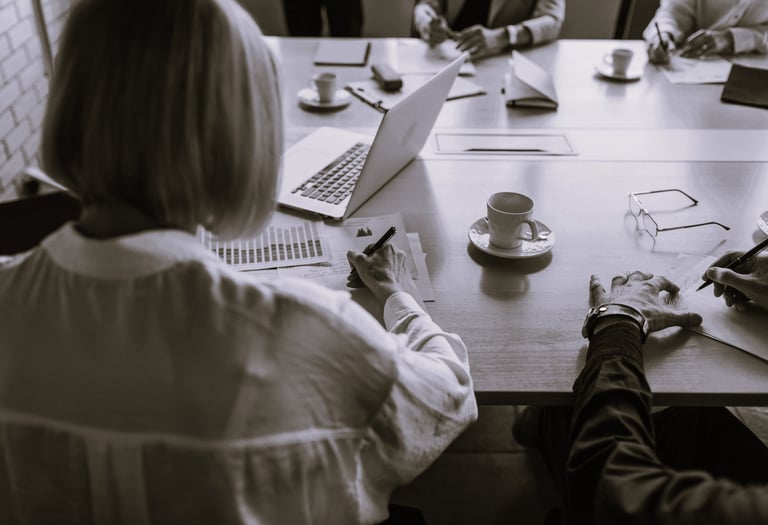 Femme assise à une table avec plusieurs personnes qui présente un projet commercial
