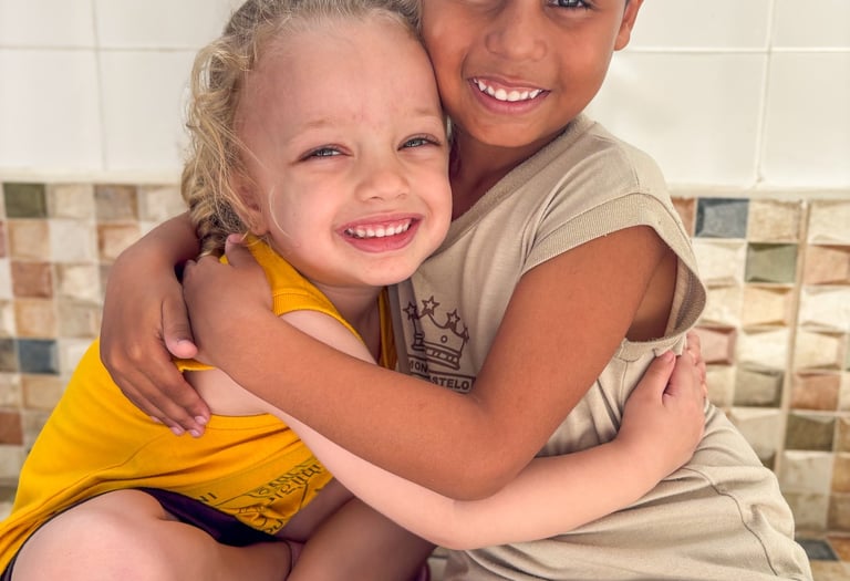 a boy and girl hugging each other on a tiled floor