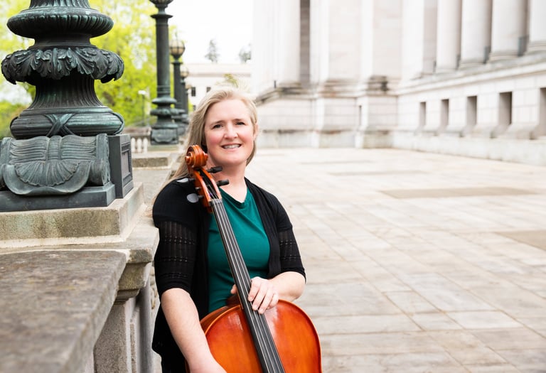 Private lesson teacher holding a cello and smiling