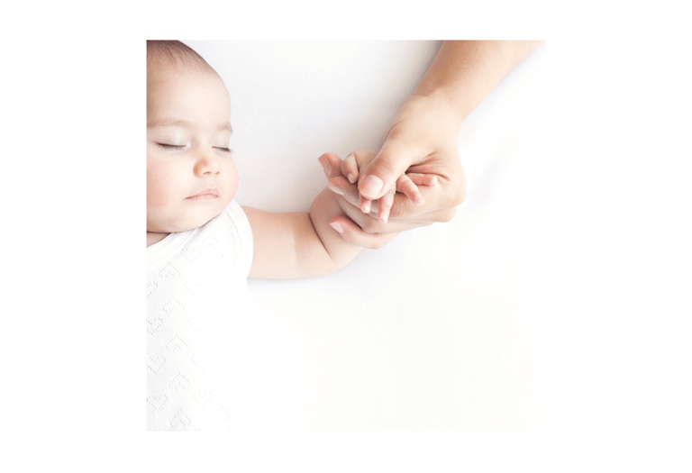 Mother holding sleeping baby's hand