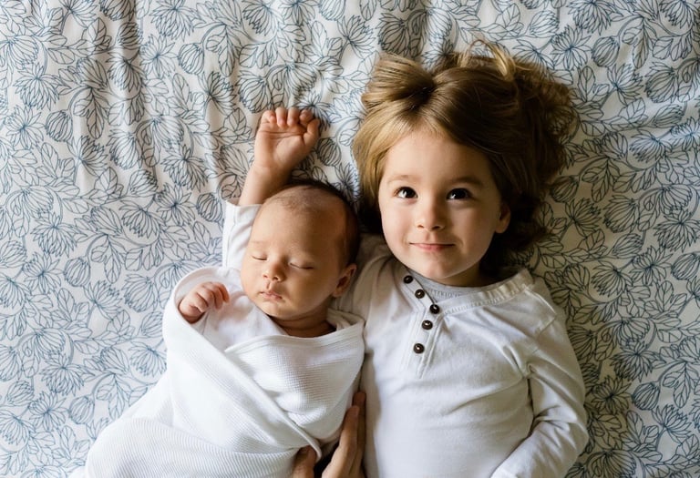 sleeping baby and older sister lying on bed