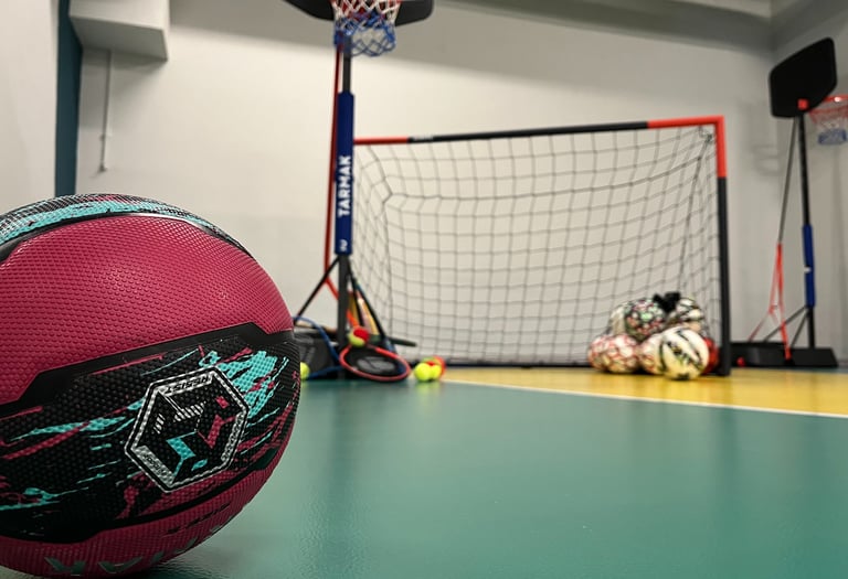 Primo piano di un pallone da basket rosa su un campo multisport nella palestra Move 2 Grow a Milano, con canestro, porta e al