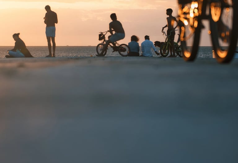 People enjoying the sunset at the beach in Mauritius, with silhouettes of bikers in the foreground.