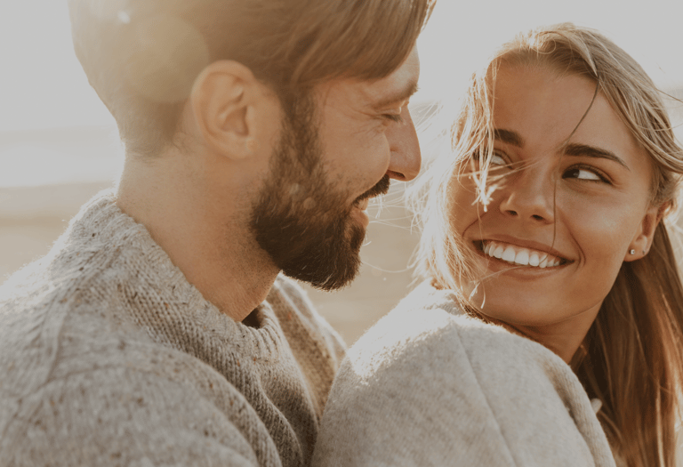 a man and woman smiling and looking at each other