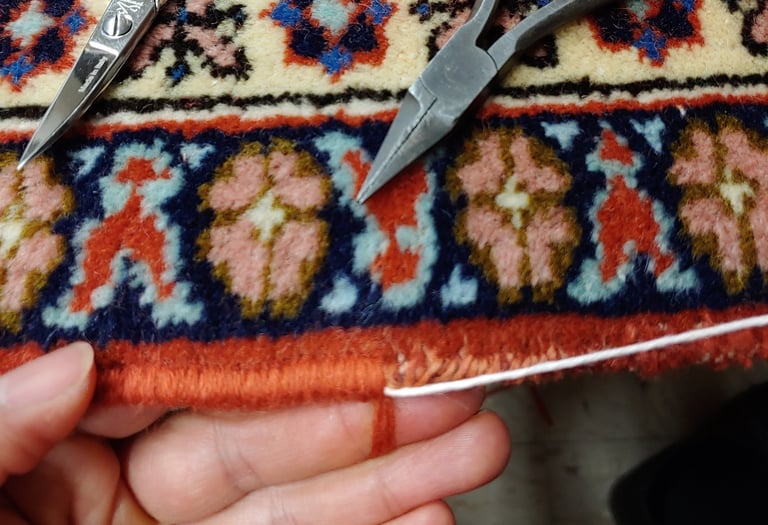 restauratore che esegue con maestria la ricostruzione dei bordi su un tappeto