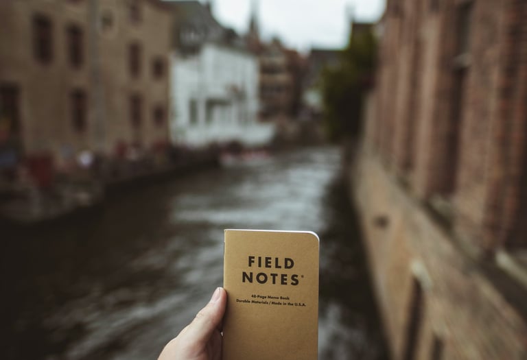 Journal titled "Field Notes" held up in front of a Canal; Photo by Vadim Sadovski on Unsplash