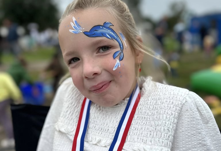 Meisje met een gedetailleerde blauwe dolfijn op haar gezicht geschminkt.