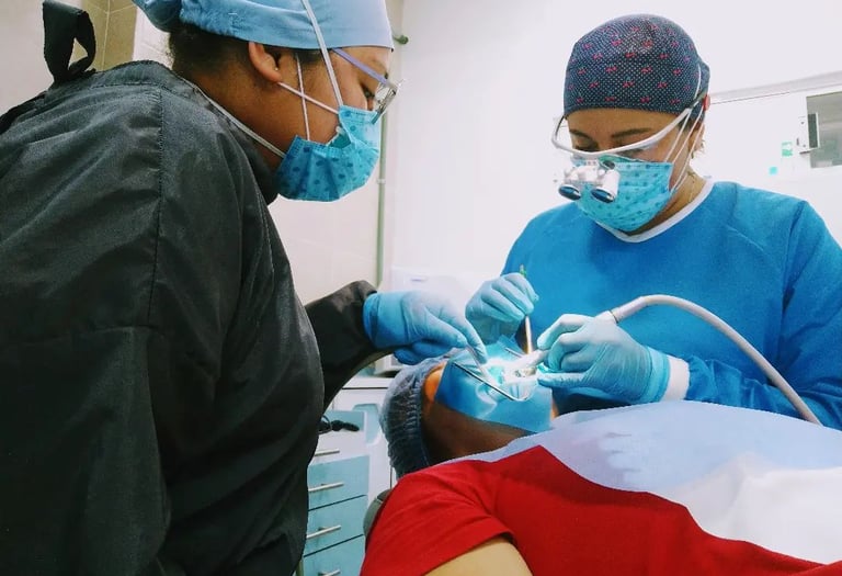 Dentista profesional y asistente realizando una cirugía dental a un paciente en una clínica.