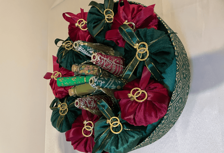 Green and burgundy velvet pouches with gold rings in a henna night favor basket.