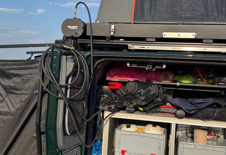 Off-road camper van setup with a rooftop tent and organized storage drawers.
