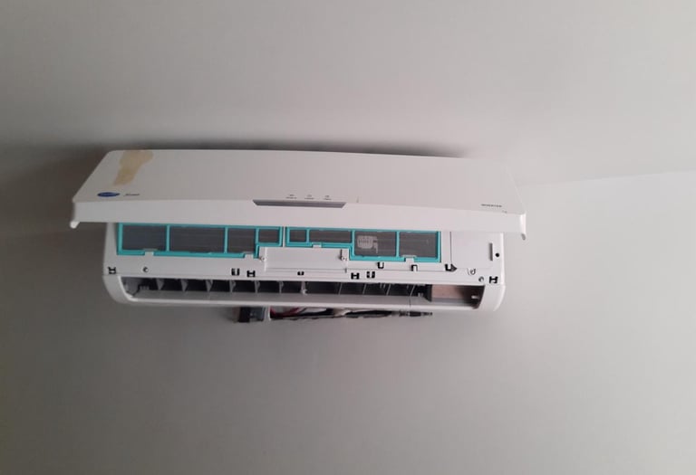 A wall-mounted Carrier split air conditioner unit with its front cover open for filter cleaning or repair.