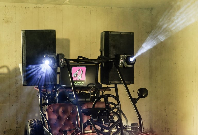 Custom DJ buggy equipped with high-powered speakers, stage lighting, and a mixer in an industrial space.