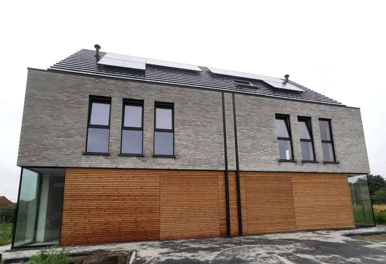 Een huis met een dak met zonnepanelen en een houten omheining.