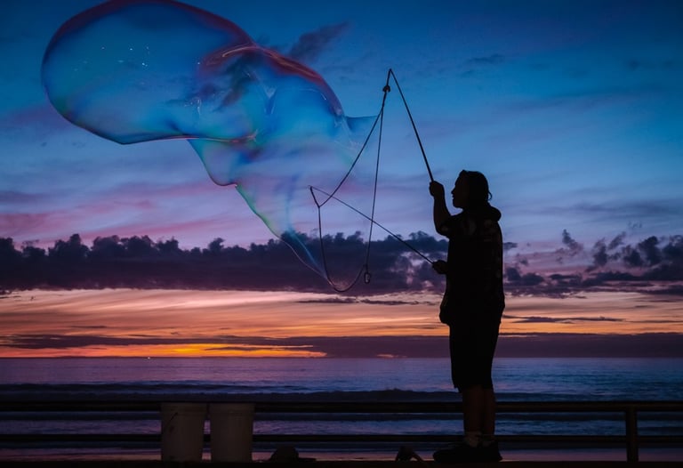 Silhouette of a man blowing giant bubbles against a sunset backdrop. Very peaceful feeling
