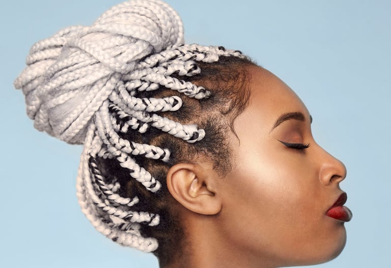 a woman with a large hairdo of white braids on a sky-blue background