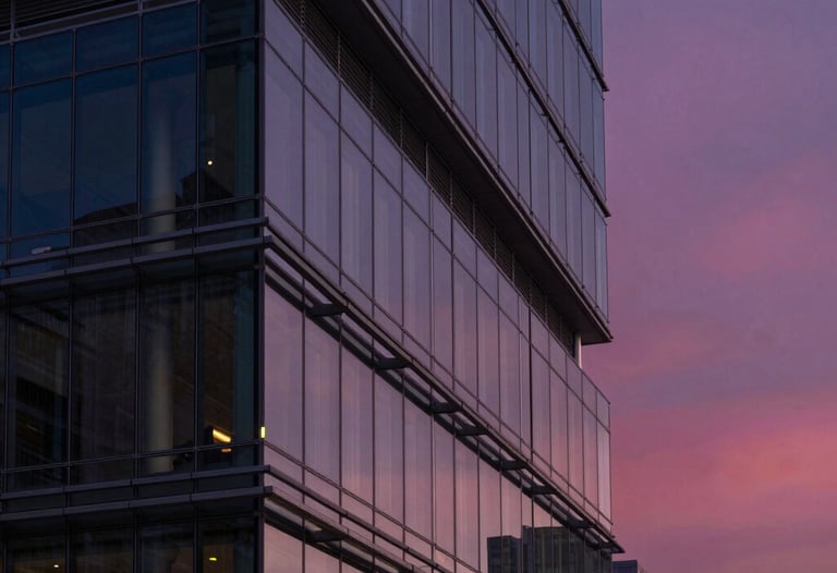 Modern architecture shot of a glass and steel building in a North American city at twilight, reflecting a deep navy and magenta sky.
