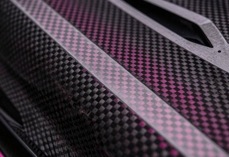 Close-up of a high-tech carbon fiber surface with magenta light catching the weave, representing elite engineering and premium design.