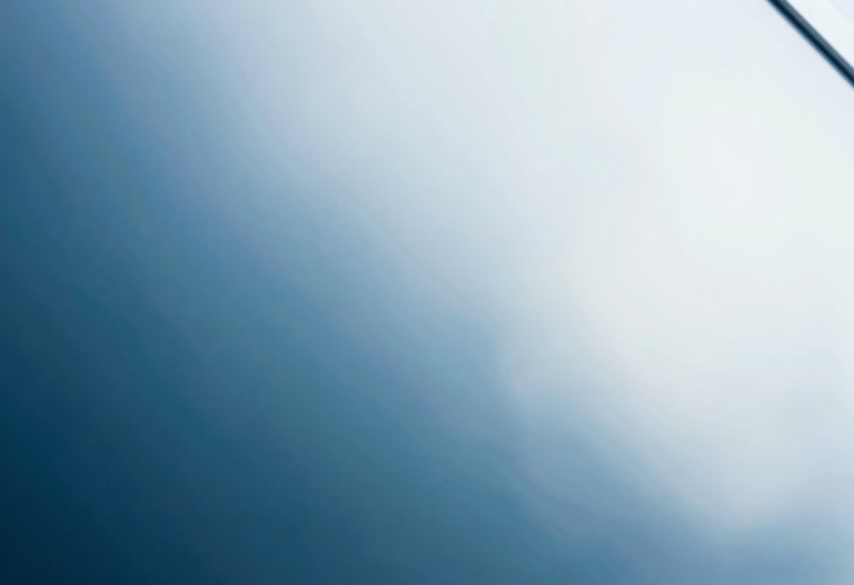 Abstract photography of light refraction through glass, creating soft blue and white gradients. Clean, minimal, futuristic.