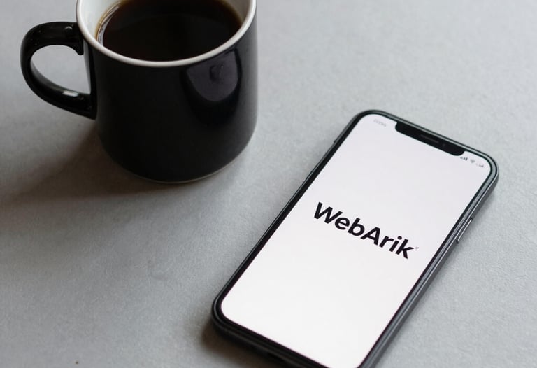 Minimalist composition of a black coffee cup and a smartphone on a light grey desk. The smartphone screen shows a clean logo 'WebArik'. Neutral, soft lighting.