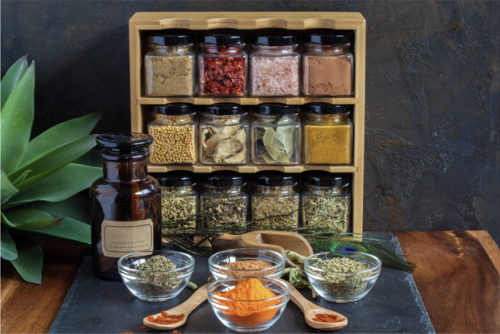 A wooden spice rack with glass jars containing colorful dried herbs and spices for kitchen organization.