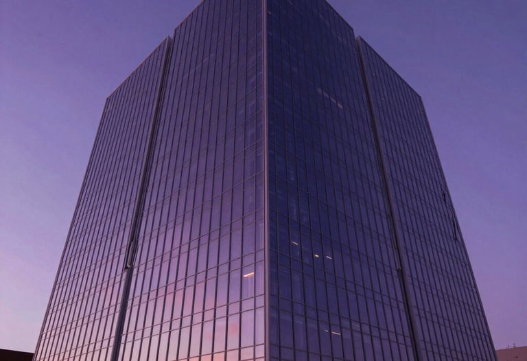 Low-angle architectural shot of a futuristic energy building in a North American setting with glass walls reflecting a deep purple sunset.