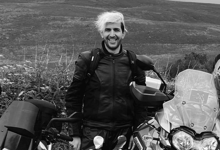 A young rider called Dan stood behind his motorcycle in a countryside landscape