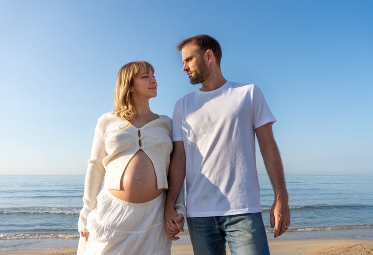 femme enceinte et son marie se tenant la main sur la plage 