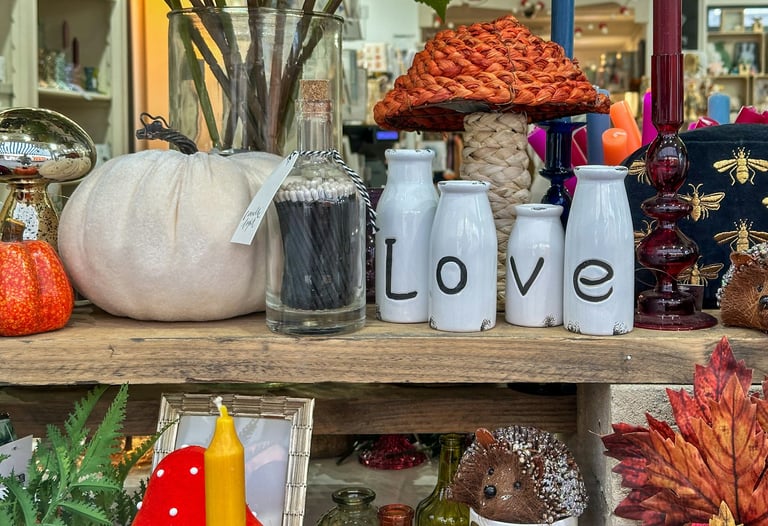 Rustic fall decor display with white pumpkins, match bottle, and Love ceramic bottles on a shelf.